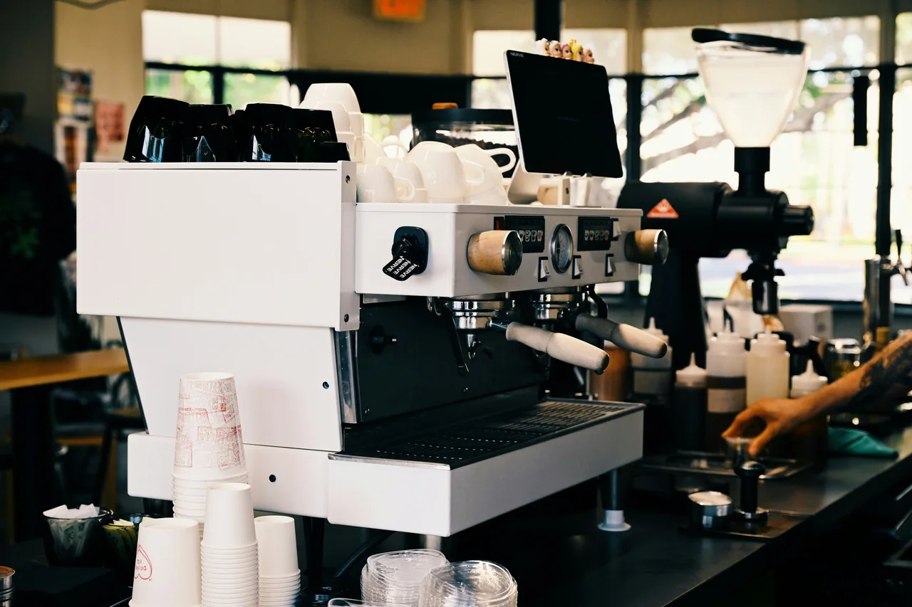 Barista menyiapkan pesanan kopi dengan mesin espresso di counter cafe