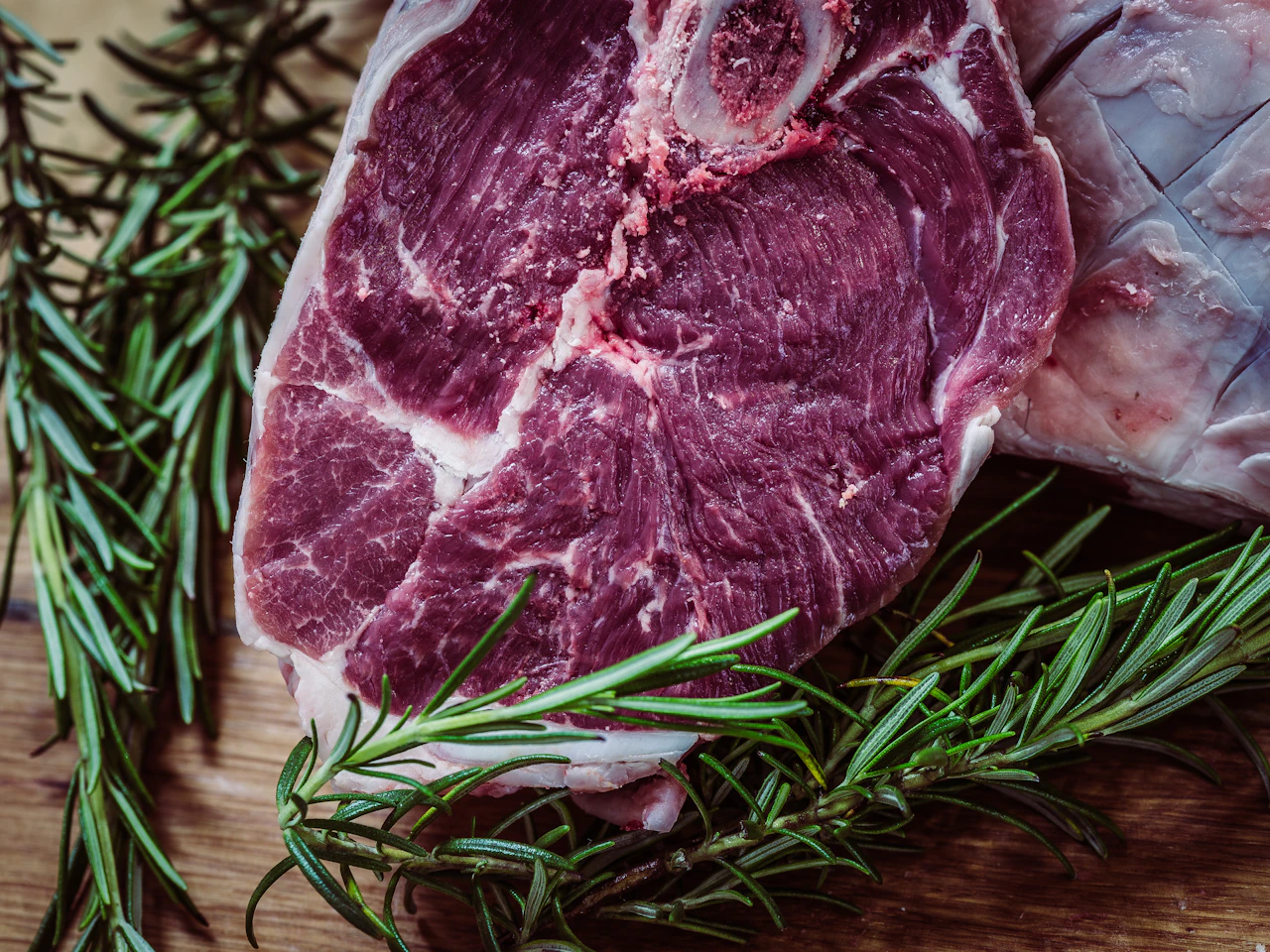 Potongan daging sapi mentah dengan daun rosemary